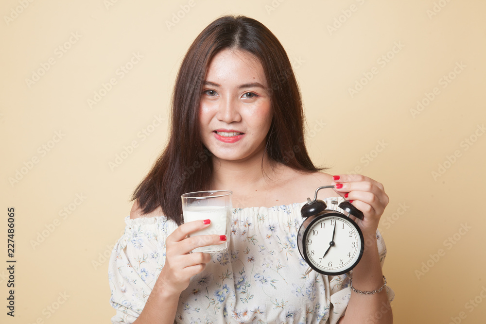 Healthy Asian woman drinking glass of milk hold clock. Healthy Asian woman drinking glass of milk hold clock.