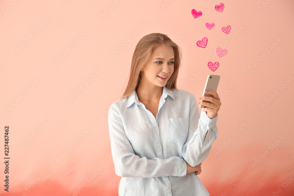 Young woman using mobile phone for online dating on pink background Young woman using mobile phone for online dating on pink background