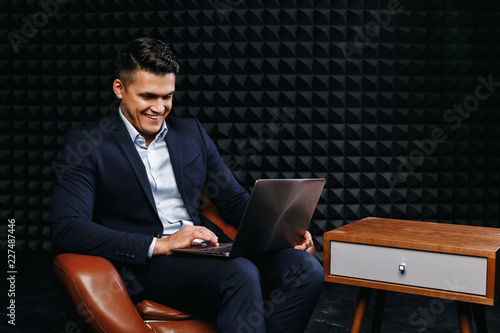 Obraz na plátně Brunette young male looking for information in computer and smiling against dark