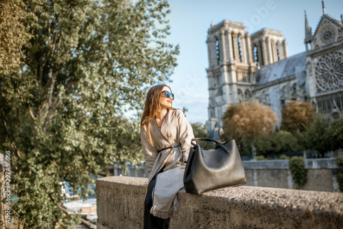 Canvas Print Young woman tourist sitting near the famous Notre Dame cathedral during the morn
