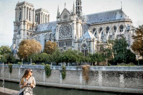 Young woman tourist sitting near the famous Notre Dame cathedral during the morning light traveling in Paris, France Fototapet