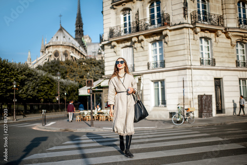 Lifestyle portrait of a stylish woman walking the street during the morning light in Paris, France