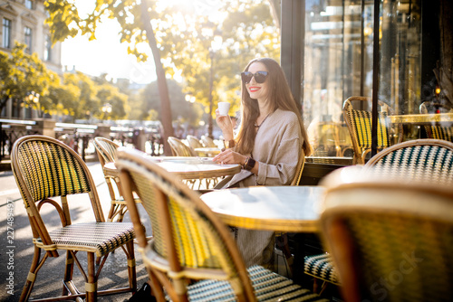 Portrait of a young woman enjoying coffee sitting outdoors at the traditional french cafe during the morning in Paris © rh2010