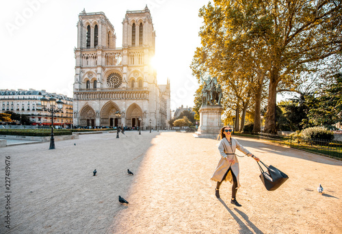 Morning view on the famous Notre-Dame cathedral with woman running on the square dispersing pigeons in Paris, France