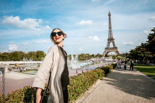 Lifestyle portrait of a young woman walking in front of the famous Eiffel tower during the sunny day in Paris