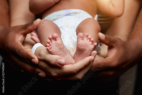 a sweet baby lying in father and mother's hands. togetherness, love, family , happiness, relationships concepts. close up portrait isolated on the black black background photo