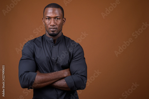 Portrait of handsome African businessman against brown background