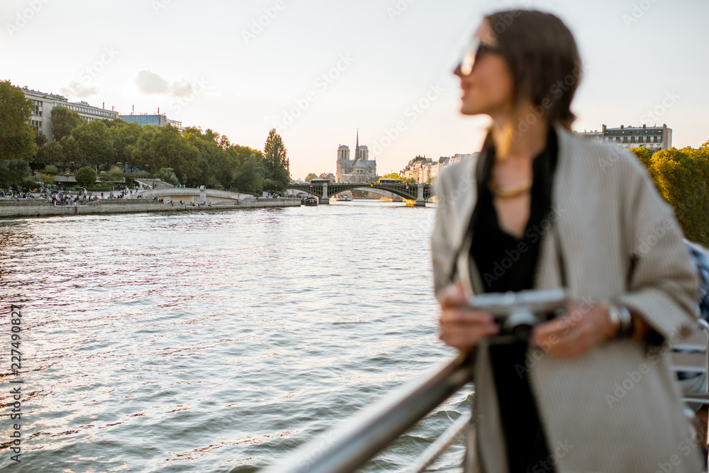 Young woman enjoying beautiful landscape view on the riverside from the ship during the sunset in Paris
