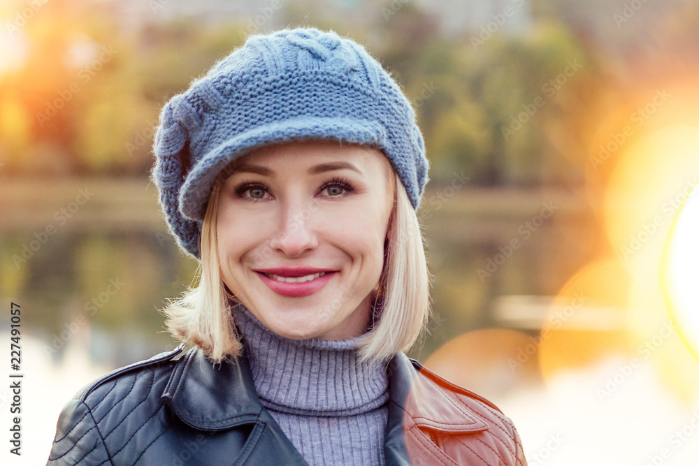 Young blonde happy smiling woman in beige coat and warm hat outdoor closeup portrait in the autumn park. Cold outside. Winter spring clothes Young blonde happy smiling woman in beige coat and warm hat outdoor closeup portrait in the autumn park. Cold outside. Winter spring clothes