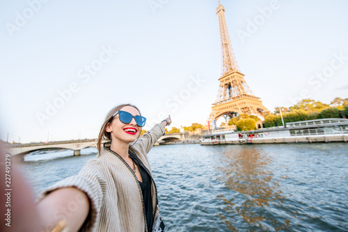 Canvas Print Young woman tourist making selfie photo with Eiffel tower on the background from