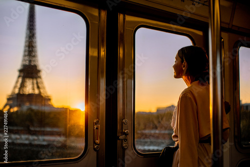 Young woman enjoying view on the Eiffel tower from the subway train during the sunrise in Paris