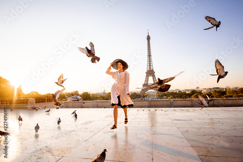 Woman running on the famous square dispersing pigeons with great view on the Eiffel tower early in the morning in Paris