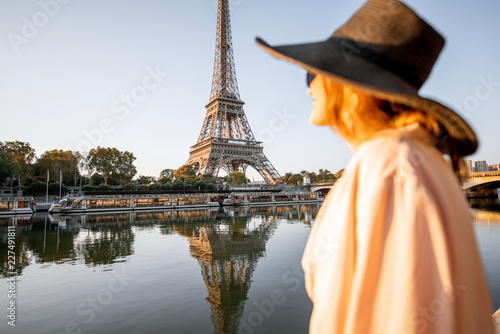 Young woman tourist enjoying landscape view on the Eiffel tower with beautiful reflection on the water during the mornign light in Paris. Image focused on the background © rh2010