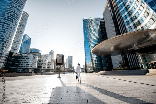 Business woman at the financial district with beautiful skyscrapers on the background during the morning light in Paris. Wide panoramic view photo