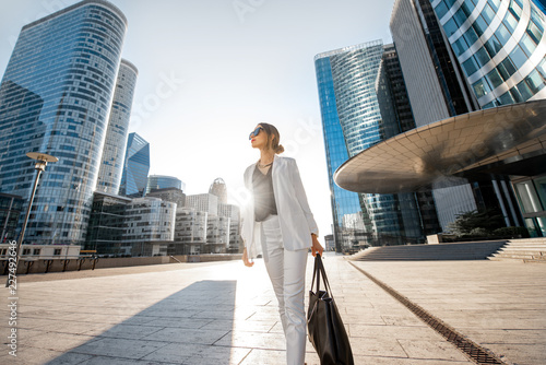 Business woman at the financial district with beautiful skyscrapers on the background during the morning light in Paris