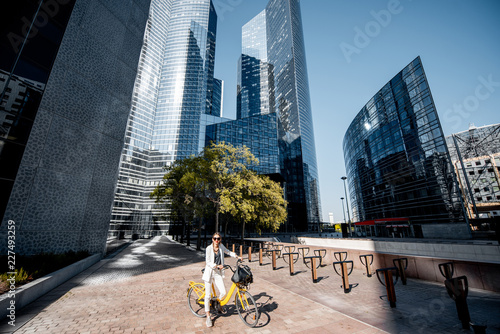 View on the financial district with business woman in white suit standing with bicycle outdoors photo