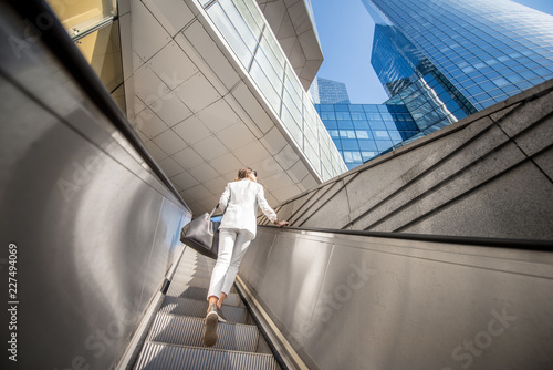 Geometrical view from below on the modern financial district with business woman going up on the escalator