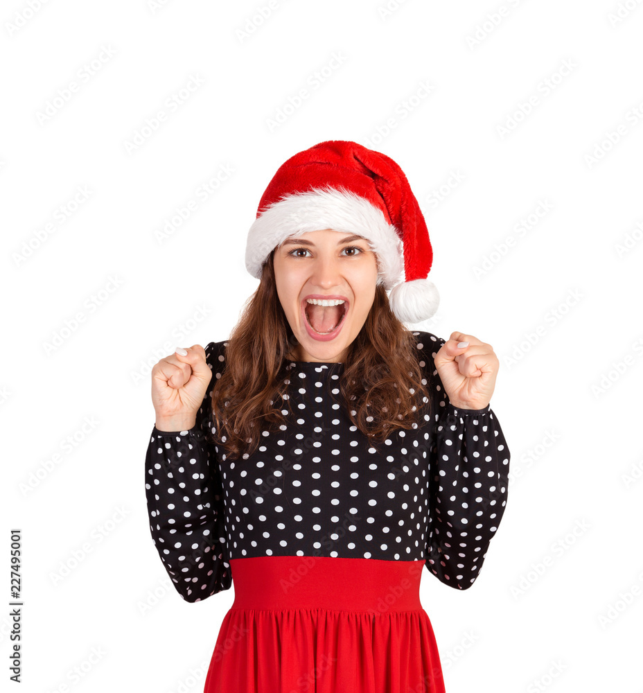 portrait of girl in dress raising hands and saying yes while celebrating goal or victory. emotional girl in santa claus christmas hat isolated on white background. holiday concept portrait of girl in dress raising hands and saying yes while celebrating goal or victory. emotional girl in santa claus christmas hat isolated on white background. holiday concept