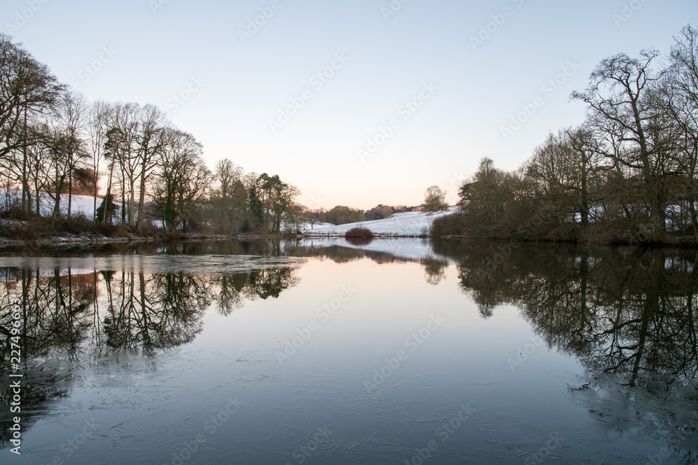 Stilllake and reflection with snow on a winter evening near Shenington, Oxfordshire, England