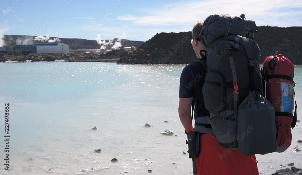 Man from backside with backpack looking at Blue Lagoon on Iceland
