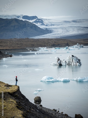 Man standing on hill watching iceberg lake landscape photo