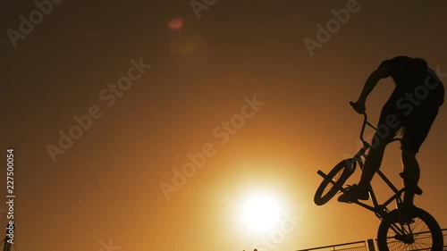 Young man doing ramp jump stunt on bmx bicycle on sunset slow motion
