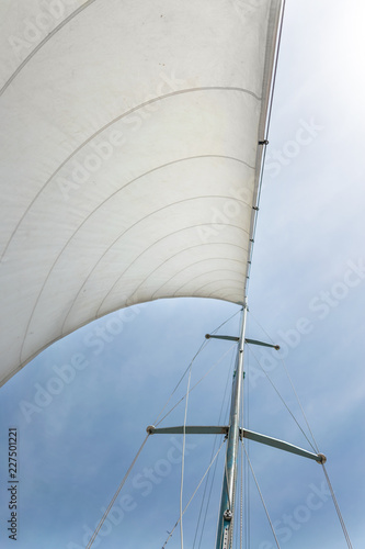 White sail of a sailing boat against sky. Sails of river sailing yacht in the wind against the blue sky