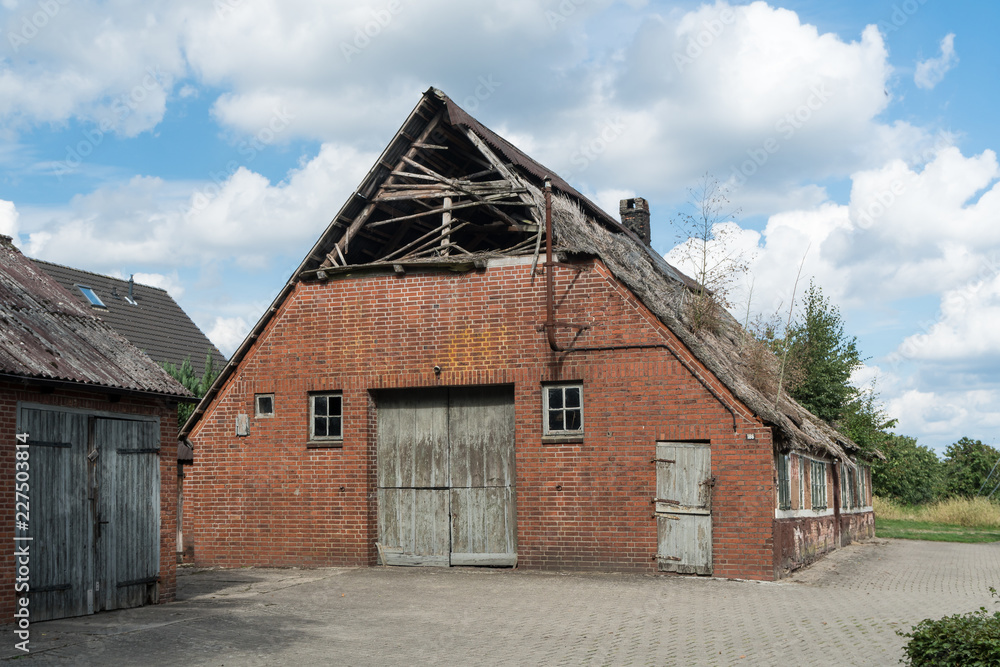 Bauernhaus mit Scheune und einem beschädigten Reetdach Bauernhaus mit Scheune und einem beschädigten Reetdach