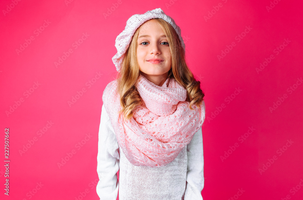 Image of happy teen girl standing isolated on pink background, in warm pink hat and warm scarf. Image of happy teen girl standing isolated on pink background, in warm pink hat and warm scarf.