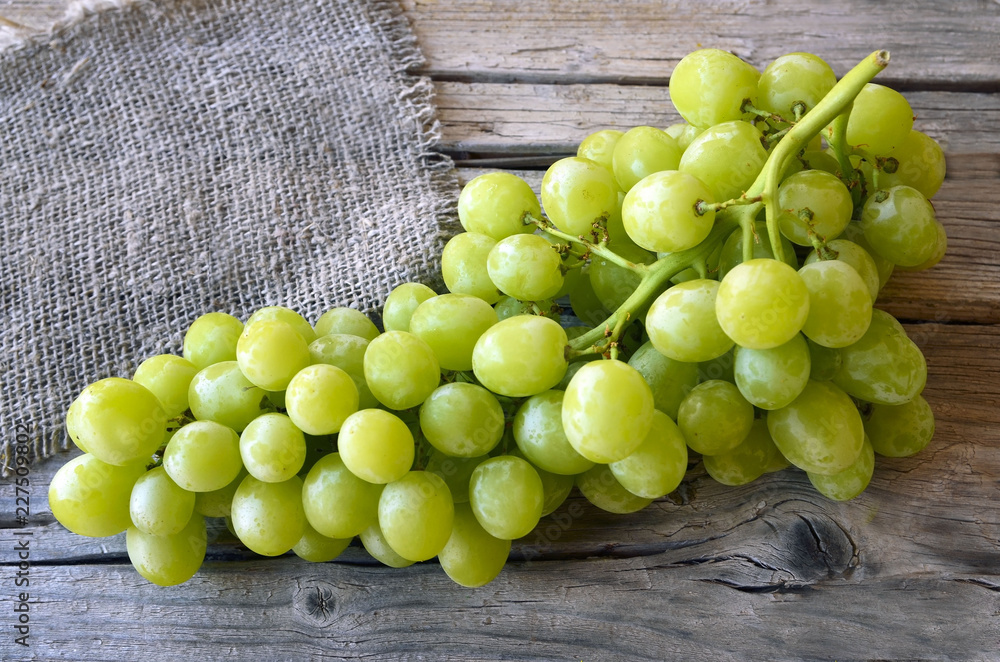 Fresh ripe green bunch of grapes ready to eat on old wooden table.Autumn harvest concept.Selective focus,copy space. Fresh ripe green bunch of grapes ready to eat on old wooden table.Autumn harvest concept.Selective focus,copy space.