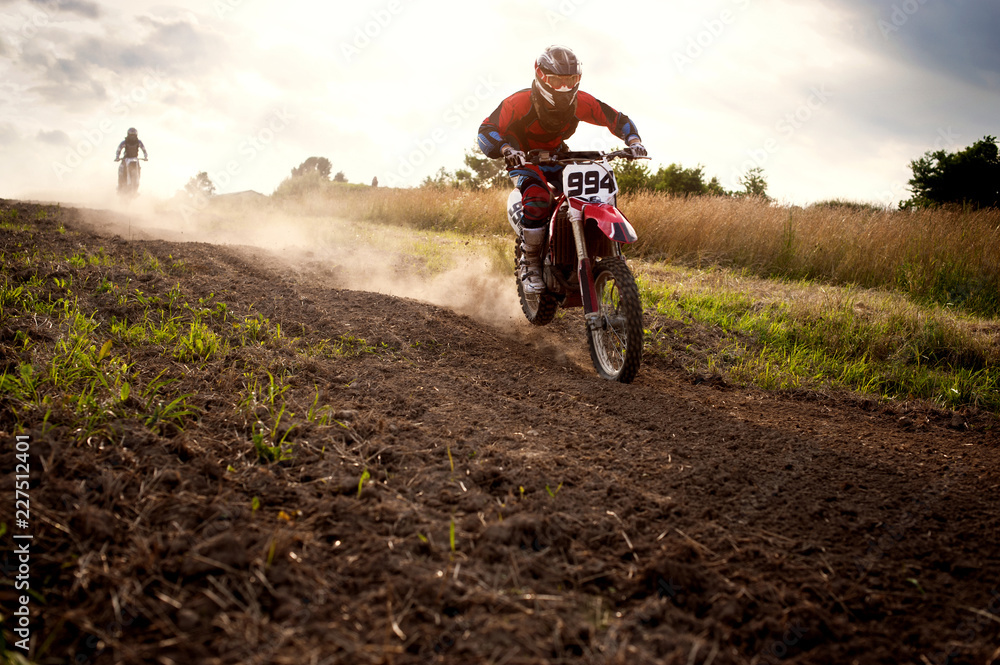 Obraz premium Dirt bikers riding motorcycles on field against sky