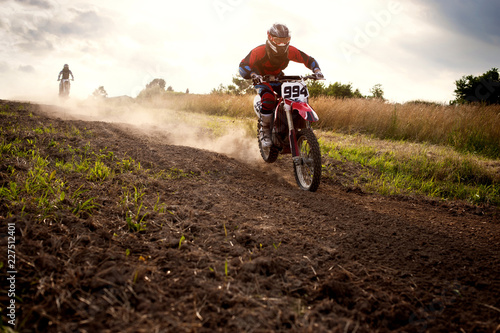 Fotografía Dirt bikers riding motorcycles on field against sky