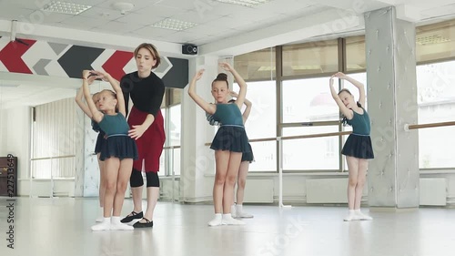 A ballet teacher teaches little ballerinas in a ballet class. teacher corrects student photo