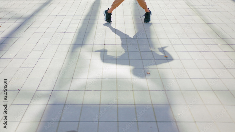 A young girl performs modern hip hop dance on the streets of the city during the summer, twisting and rotating. A young girl performs modern hip hop dance on the streets of the city during the summer, twisting and rotating.