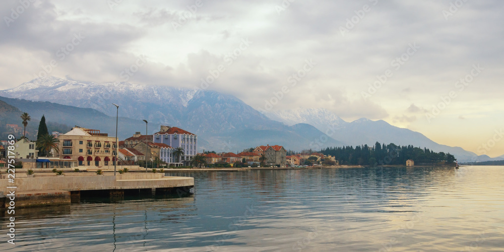 Beautiful Mediterranean landscape on cloudy winter day. Montenegro, embankment of Tivat city and snow-capped peaks of Lovcen mountain