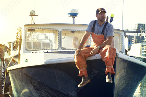 Fisherman looking away while sitting on trawler