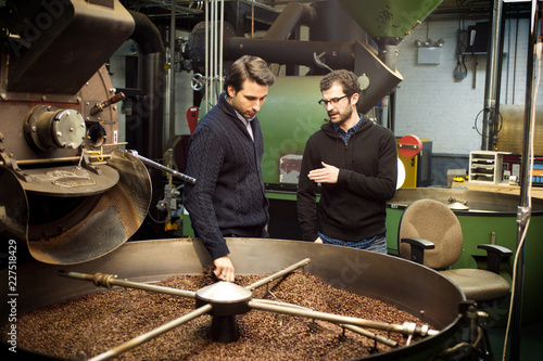 Slika na platnu Colleagues discussing while standing by coffee roaster