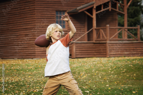 Quadro su tela Boy throwing football while playing in park