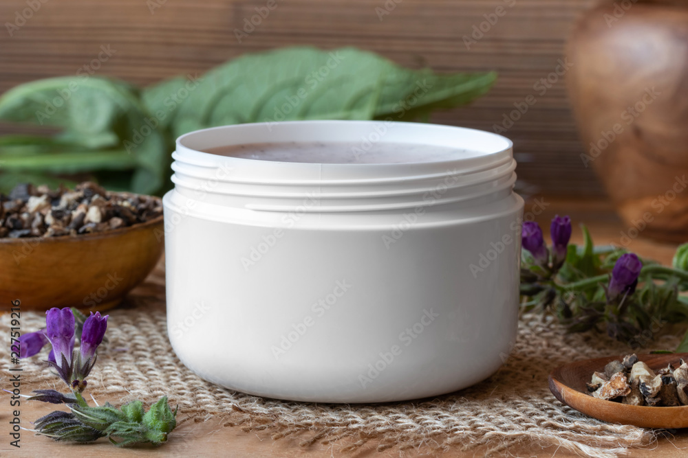 A jar of homemade comfrey root ointment with fresh symphytum plant A jar of homemade comfrey root ointment with fresh symphytum plant