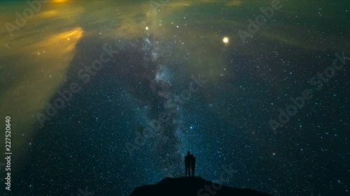 The couple standing on a night mountain with a starry sky background. time lapse