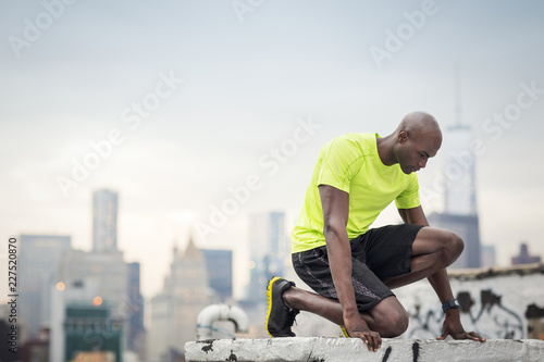 Male athlete kneeling at building terrace, USA