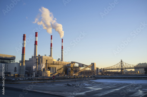 Obraz na plátne Smoke stacks in factory by bridge, New York, USA