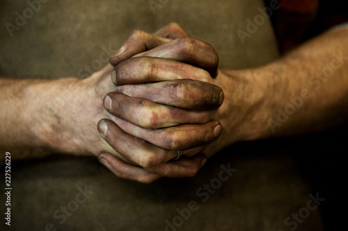 Messy clasped hands of blacksmith