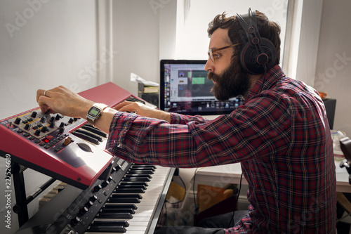 Φωτογραφία Man with headphones adjusting synthesizer