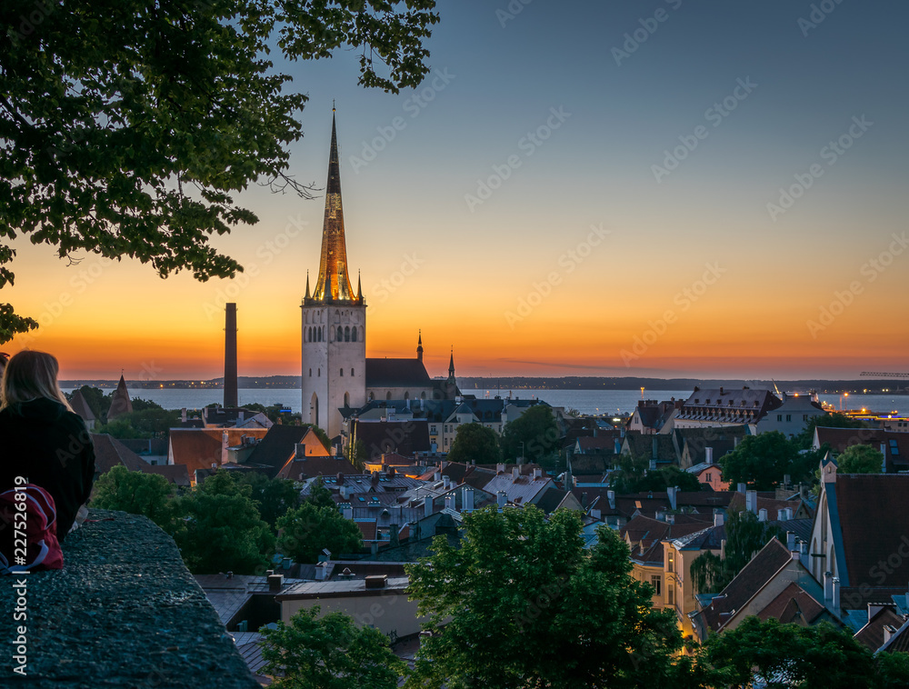 people enjoying a view of Tallinn roof tops and church spires at dawn.