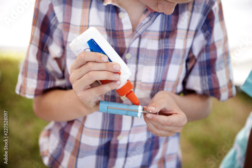 Εκτύπωση καμβά Boy applying glue on object while making craft at park