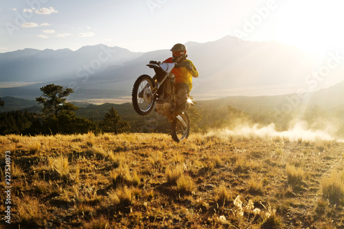 Dirt biker performing stunt on field against sky