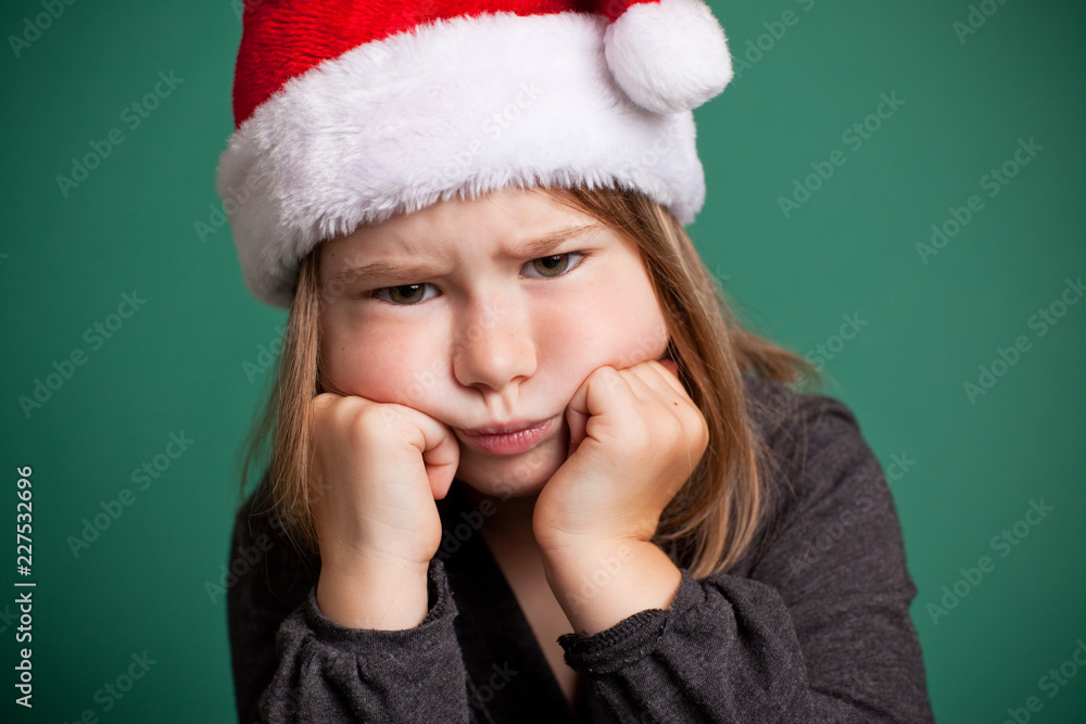 Grumpy Christmas Girl in Santa Hat, Isolated on Green Grumpy Christmas Girl in Santa Hat, Isolated on Green