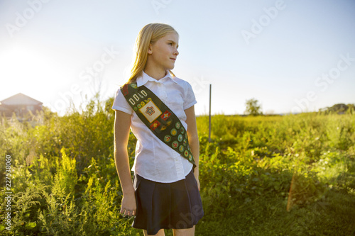 Photography Thoughtful schoolgirl in sash standing on field