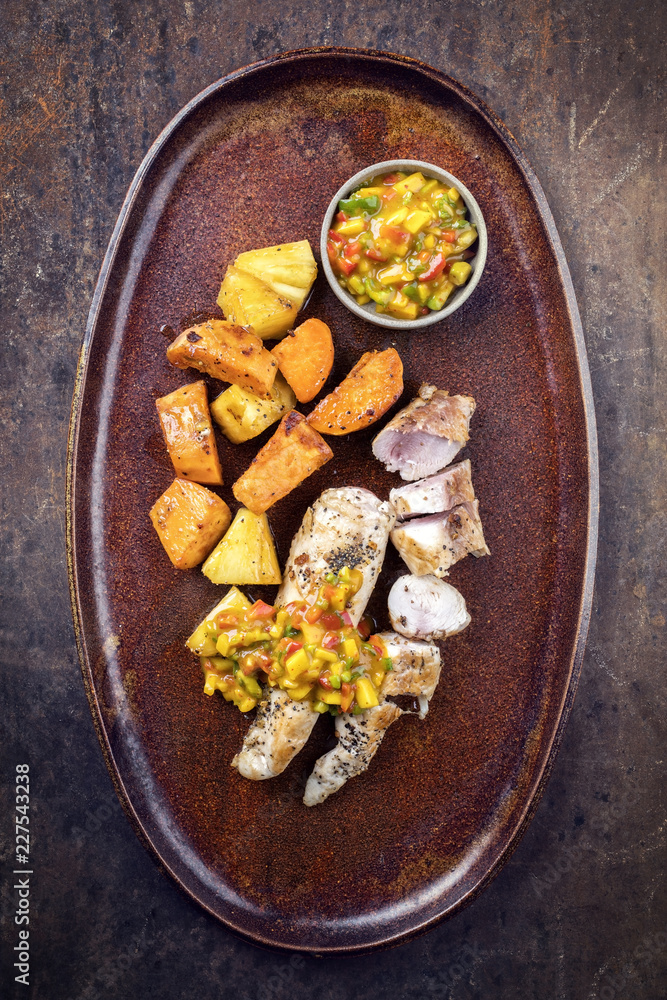 Modern barbecue crocodile tail eye fillet with roasted sweet potatoes pineapples and mango chili chutney as top view on a plate Modern barbecue crocodile tail eye fillet with roasted sweet potatoes pineapples and mango chili chutney as top view on a plate